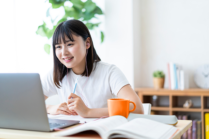 Young woman with earbuds working on laptop