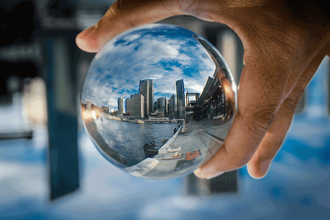 City skyline reflected in a glass sphere held in a hand by the waterfront